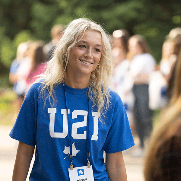 A female student with blonde hair wearing a blue ISU T-shirt smiles